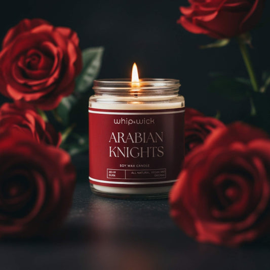 Whipandwick Arabian Knights soy wax candle in a red glass jar, lit and surrounded by deep red roses against a dark, elegant background.